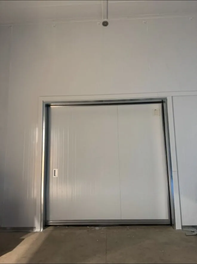 Bi-parting sliding freezer door for a cold storage warehouse